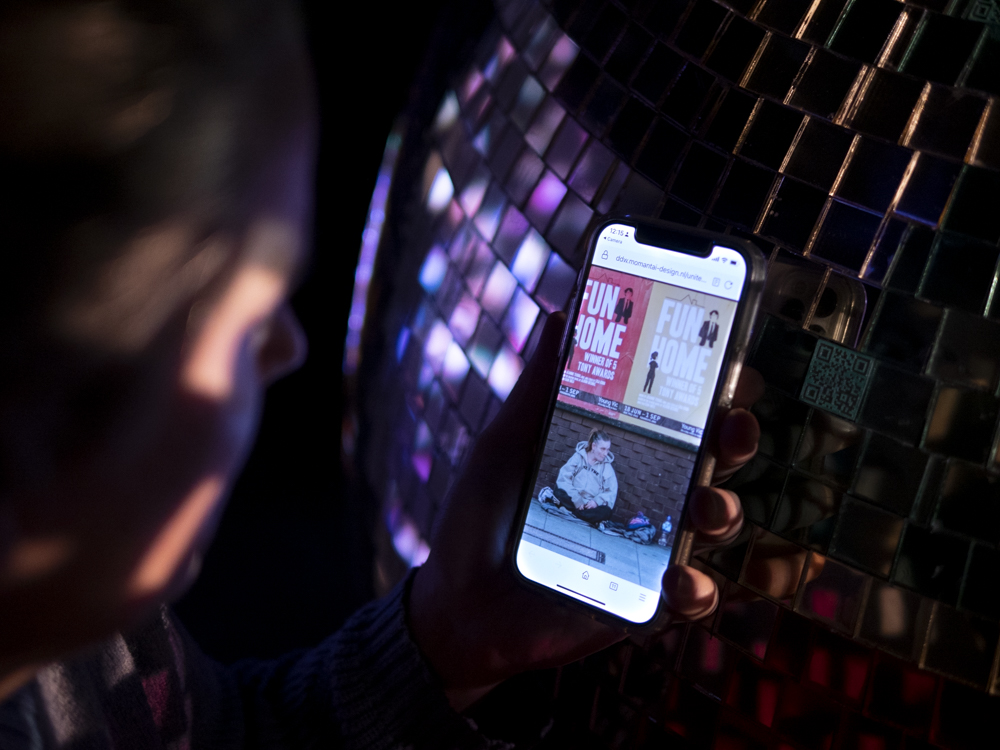 scanning a QR CODE at the purple section of the bright future installation by momantai studio. Which show you a world problem, in this case a homeless person