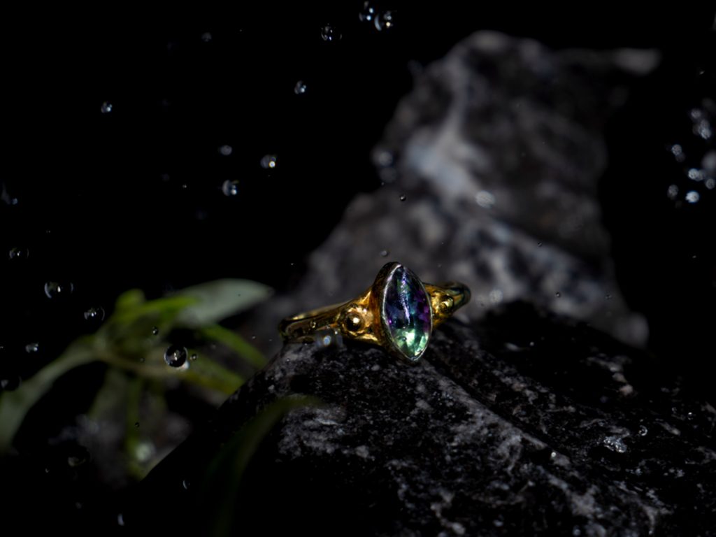 mermaid series product photography, of jewellery. A ring lying on the rocks with water flying all around.