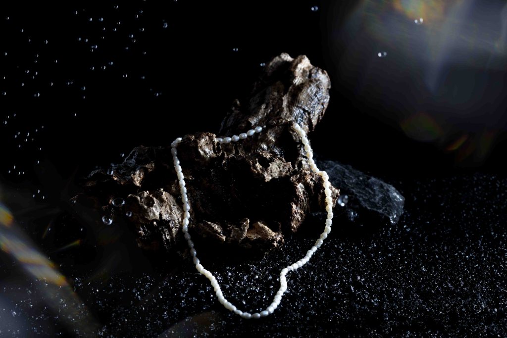 Een foto voor waterproof sieraden dit is een parelketting op een stuk hout met water